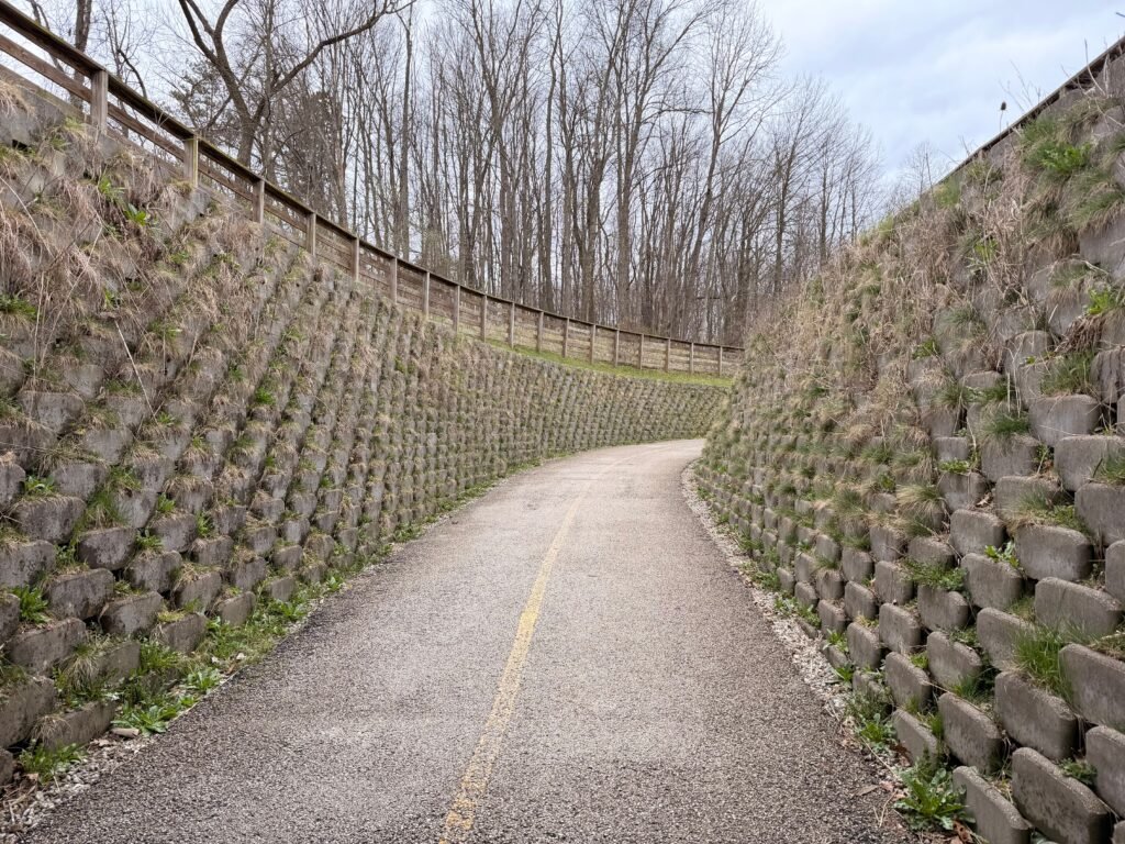 A serene pathway winding between stone walls and bare trees, inviting a tranquil walk.